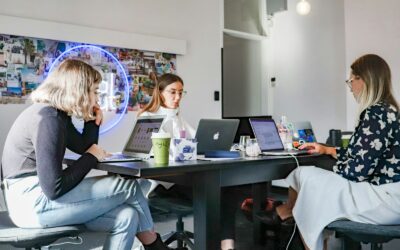 3 femmes assises sur une chaise devant une table avec des ordinateurs portables