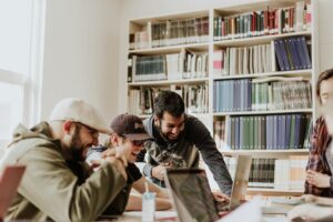 trois hommes rient en regardant l'ordinateur portable à l'intérieur de la pièce