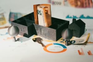 Les billets en euros avec un modèle de maison et des graphiques financiers symbolisent l'investissement immobilier et la croissance économique.