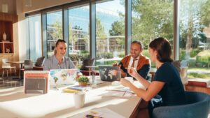 Trois collègues réfléchissent avec des ordinateurs portables dans un bureau bien éclairé.