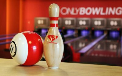Bowling ball rouge et blanc à côté d'une patte, allée et enseigne visibles