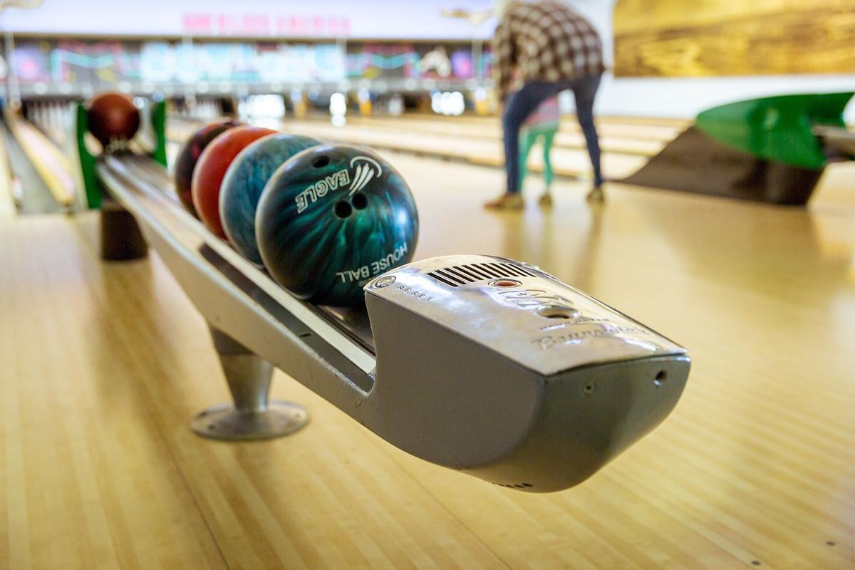 Balle de bowling sur le retour, allée, joueur en arrière-plan Balle de bowling sur le retour, allée, joueur en arrière-plan