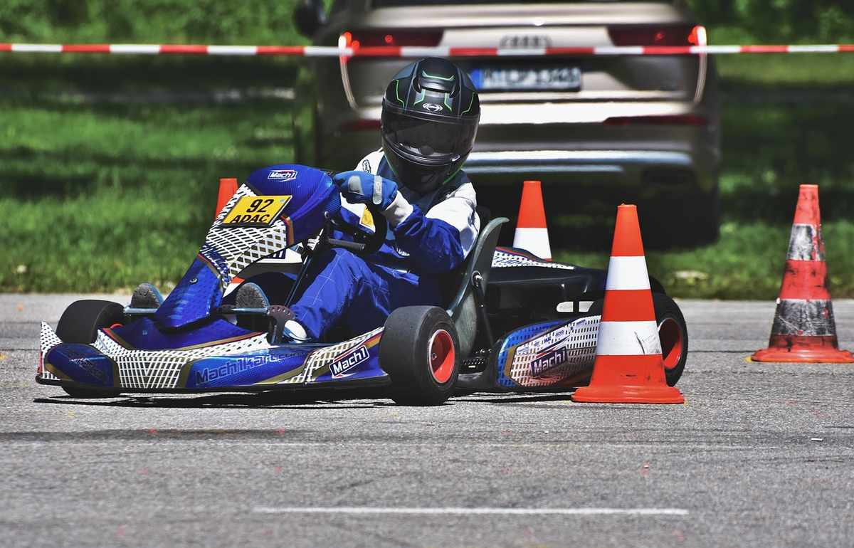 Un conducteur en karting bleu négocie un virage entre cônes orange