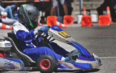 Un conducteur en kart bleu et casque pilote sur circuit avec cônes